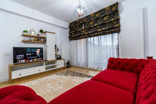 a living room with a red couch and a tv at Lighthouse Central Apt with unique views of the Fortress, Free Parking, 5 min by car from the Old Town in Braşov