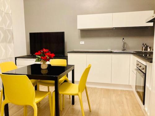 a kitchen with a black table and yellow chairs at MALU LUXURY APARTMENTS in Rimini