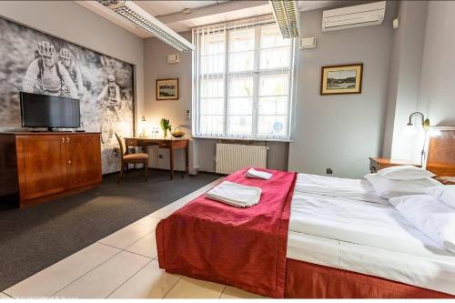 sypialnia z dużym łóżkiem, biurkiem i telewizorem w obiekcie VILLA CAPITOL w Ostródzie
