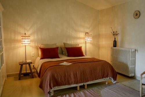 a bedroom with a bed with red pillows and two lamps at Mas des Prêcheurs in Tarascon