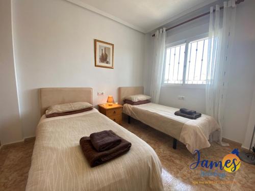 1 dormitorio con 2 camas y ventana en La Ciñuelica, R3 1st Floor Apartment Com Pool L129, en Torrevieja