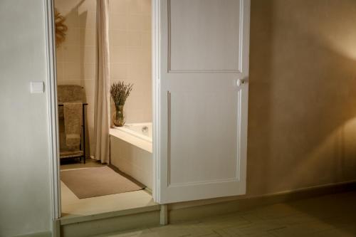 a bathroom with a tub and a white door at Mas des Prêcheurs in Tarascon