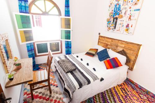 a bedroom with a bed and a table and a window at La casa de papel in Essaouira