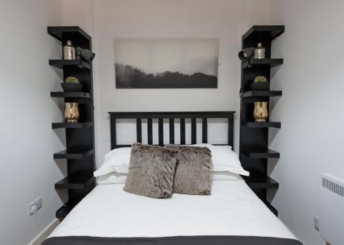 a bedroom with a white bed with black shelves at The Blakeney in Leicester