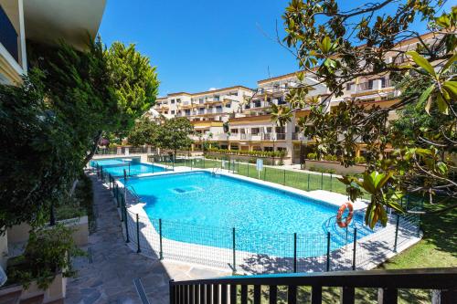 uma imagem de uma piscina em frente a um edifício em Romana Playa 132 Apartment by GHR Rentals em Marbella