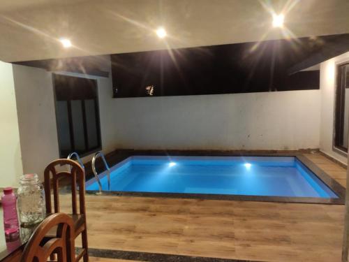 a large swimming pool in a room with a table and chairs at Bliss Villa 6Bhk Alibaug 1 Min Walking Distance To Kihim Beach in Alibaug