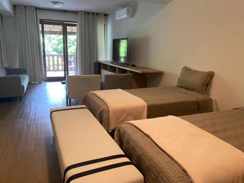 a hotel room with three beds and a television at Lendas do Capão Pousada in Vale do Capao