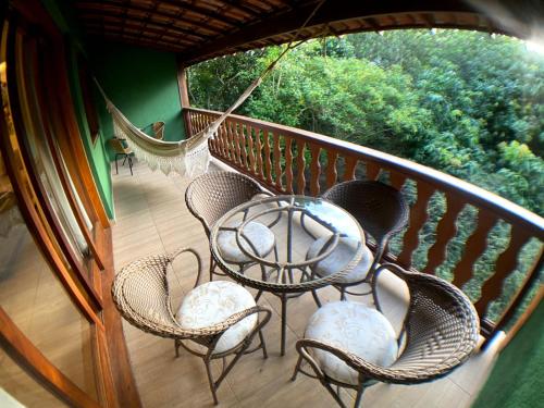 a balcony with a table and chairs and a hammock at Lendas do Capão Pousada in Vale do Capao
