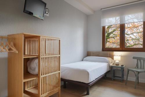 a small bedroom with a bed and a tv on the wall at Hostal Rural Aritzalko in Echarri-Aranaz