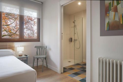 a bedroom with a shower and a bed and a chair at Hostal Rural Aritzalko in Echarri-Aranaz
