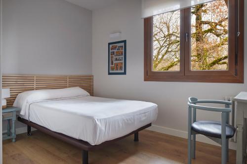 a bed in a room with a chair and a window at Hostal Rural Aritzalko in Echarri-Aranaz