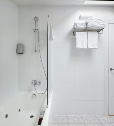 a white bathroom with a shower and towels at Hostal Rural Aritzalko in Echarri-Aranaz