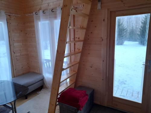 Habitación con escalera en una cabaña de madera con 2 ventanas en Koobamäe saunamaja en Kulli