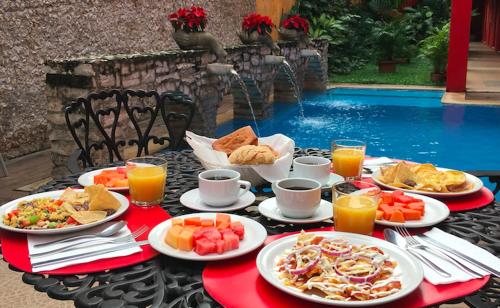 a table with plates of food and orange juice at Hotel Mejorada Merida in Mérida