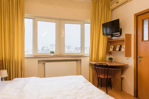 1 dormitorio con 1 cama, escritorio y 2 ventanas en Downtown Studio, en Bucarest