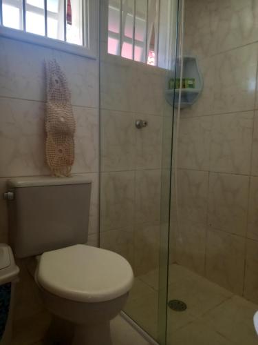 a bathroom with a toilet and a glass shower at Pousada Casa Amarela in Piracaia