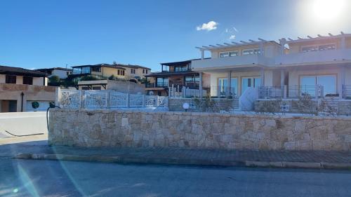 Cette grande maison blanche est dotée d'un mur en pierre. dans l'établissement Aqualife2 luxury Apartment, à Arzachena