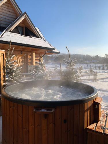 a hot tub in the snow next to a cabin at "Osada Guty" - Domki z Jacuzzi - Szaflary in Szaflary