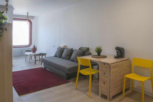 Apartamento Estación Manzaneda في Prada: غرفة معيشة مع أريكة وطاولة وكراسي