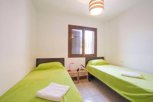 カルプにあるBungalow Salud - PlusHolidaysのベッド2台 緑のシーツ、窓が備わる客室です。