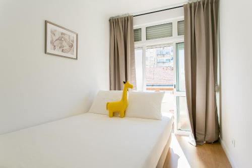 a bedroom with a white bed with a toy giraffe on it at City Retreat in Lisbon