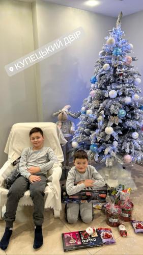 a man and boy sitting in chairs in front of a christmas tree at Купецький Двір in Mizhhirʼʼya