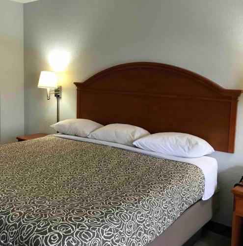 a bed in a hotel room with two pillows at Walnut Inn - Checotah in Checotah