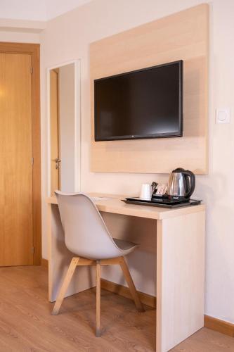a room with a desk with a chair and a television at The Originals City, Hôtel Mondial, Perpignan in Perpignan