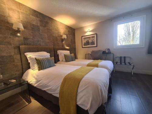 een hotelkamer met 2 bedden en een raam bij Hotel Acadie Eragny in Éragny