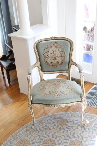 a chair sitting in a room with a rug at An English Garden in Dennis Port