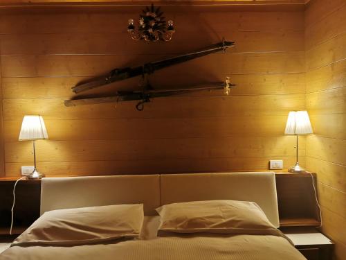 a bedroom with a bed with two lamps and a plane on the wall at Chalet nel bosco in Borca di Cadore