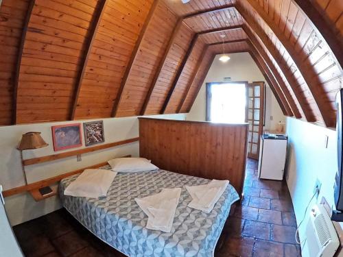 ein Schlafzimmer mit einem Bett in einem Zimmer mit Holzdecken in der Unterkunft Pousada Verde Agua in São Lourenço do Sul