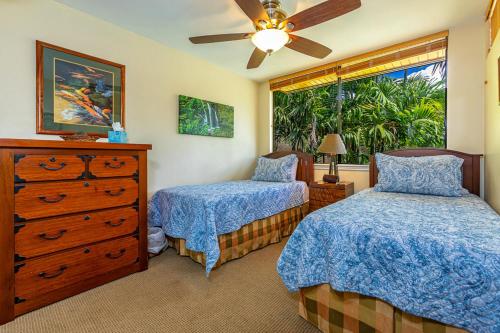 a bedroom with two beds and a dresser and a window at Kamaole Beach Club C109 in Kihei