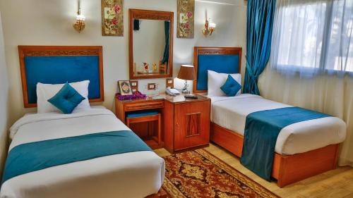 Habitación de hotel con 2 camas y espejo en The Palm Hotel, en Kafr EL Sheikh