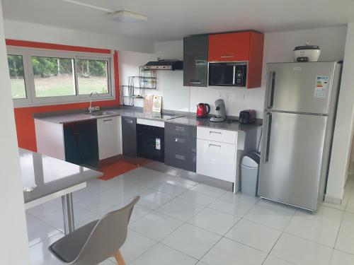 a kitchen with a stainless steel refrigerator and red cabinets at L'échappée belle in Port-Louis