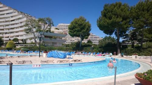 une piscine avec des chaises et des gens dans l'eau dans l'établissement Appartement bord de mer Marina Baie des Anges, à Villeneuve-Loubet