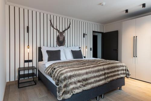 Dormitorio con cama con cabeza de ciervo en la pared en Residenz Boutique Suites en Bad Gastein