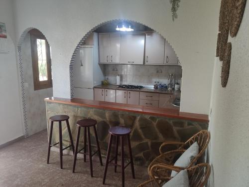 una cucina con bancone e sgabelli in una stanza di Encantadora casa rural con gran porche a San Roque