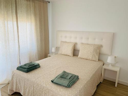 ein Schlafzimmer mit einem Bett mit einem grünen Handtuch darauf in der Unterkunft Torre del Este, Santa Pola in Santa Pola