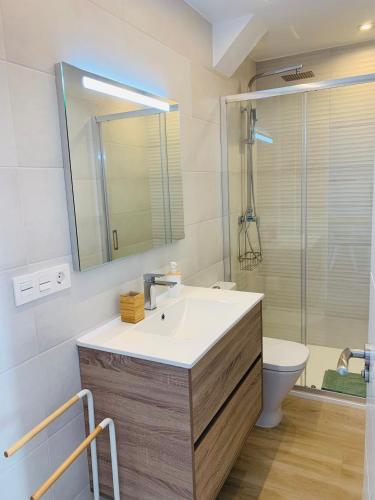 a bathroom with a sink and a toilet and a mirror at Torre del Este, Santa Pola in Santa Pola