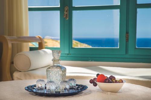 a table with a glass bottle and a bowl of fruit at Mohlos Villas in Mochlos