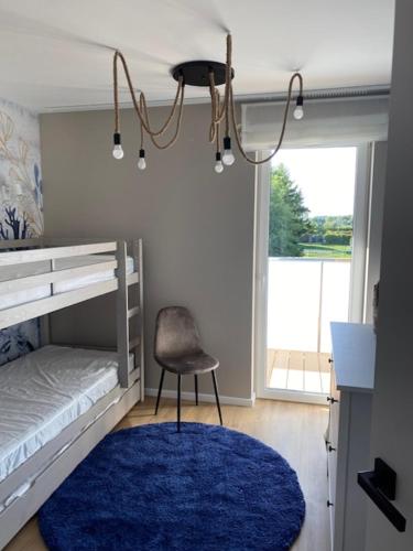 a bedroom with a bed and a chair and a blue rug at Baltic Apartment Posesja Kapitańska in Grzybowo