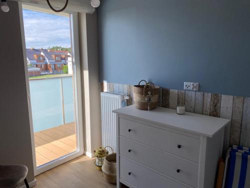 a white dresser in a room with a balcony at Baltic Apartment Posesja Kapitańska in Grzybowo