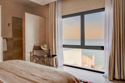 a bedroom with a large window with a view of the ocean at Hôtel Oasis Dakhla in Dakhla