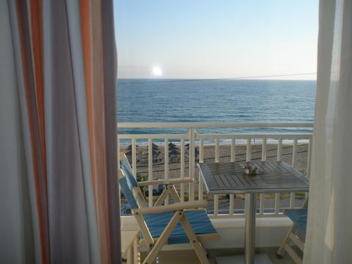 a balcony with a table and a view of the ocean at Haris Hotel Apartments and Suites in Paralia Vrachou