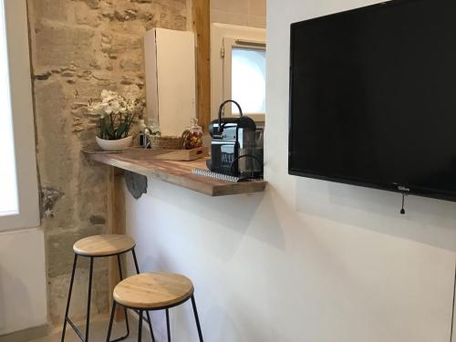 une cuisine avec deux tabourets et une télévision murale dans l'établissement Loft avec beaucoup de cachet centre historique Montpellier, à Montpellier