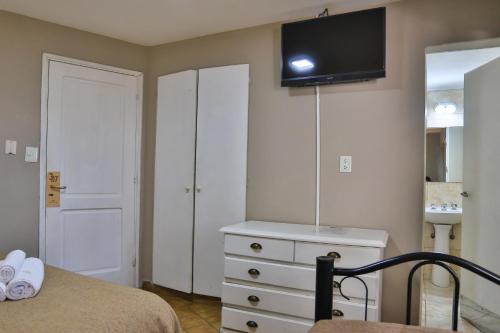 a bedroom with a bed and a dresser with a tv on the wall at Trip Bariloche Select in San Carlos de Bariloche