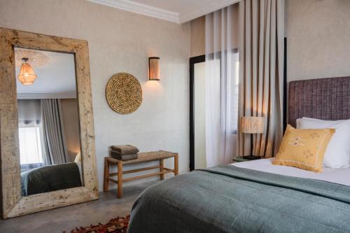 a bedroom with a bed and a mirror and a chair at Hôtel Oasis Dakhla in Dakhla