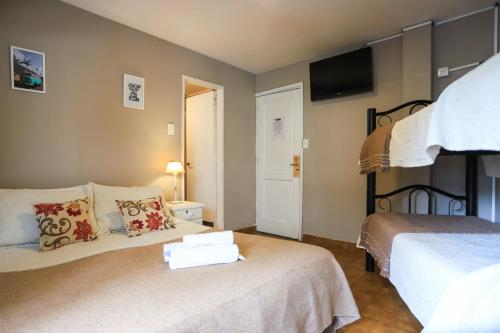 a bedroom with two beds and a tv on the wall at Trip Bariloche Select in San Carlos de Bariloche