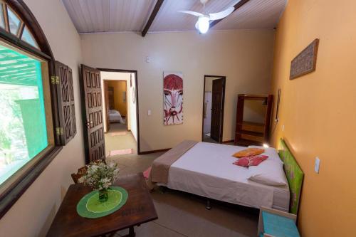 a bedroom with a bed and a table and a window at Chale Kangaroos Imbassai in Imbassai